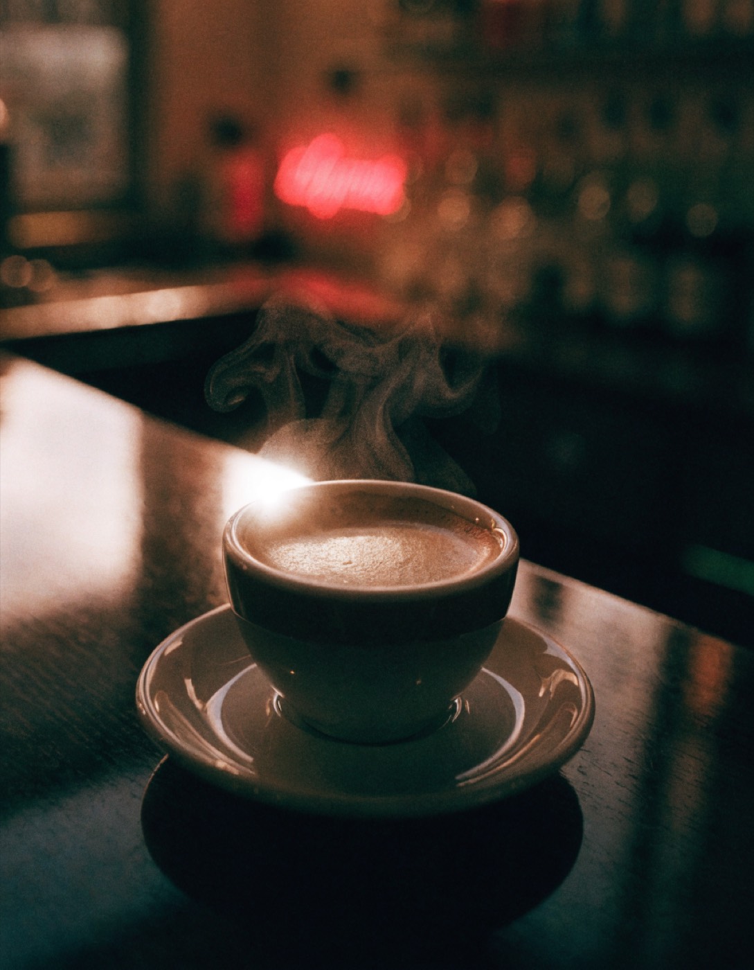 A steaming espresso on a dark bar, red neon behind it, about how long your first answer takes